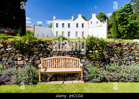 Sedia da giardino in un giardino formale accanto a una grande casa bianca. Foto Stock