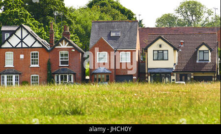 Case in la strada verde fotografato guardando attraverso il verde, Theydon Bois, Essex Foto Stock