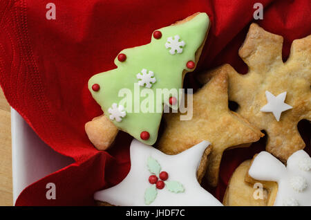 Scatto dall'alto di una selezione di casa cotto biscotti di Natale (cookies) di glassa (glassa) e gli elementi decorativi. Servita nel quadrato bianco ciotola wi Foto Stock