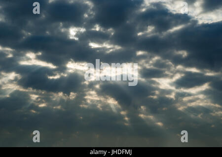 Minacciando, minacciosa grigio scuro sky con pochi raggi del bianco luminoso con la luce del sole fa capolino attraverso uno spazio tra le nuvole. Foto Stock