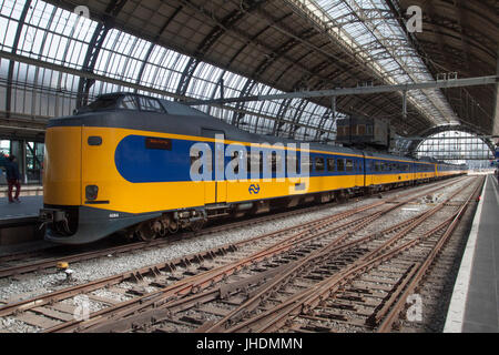 AMSTERDAM, Paesi Bassi - 24 Maggio 2017: Attesa olandese società ferroviarie sul treno la stazione ferroviaria con il vecchio curvo in ghisa costruzione del tetto Foto Stock