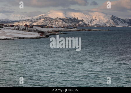 Case sul Holdoya-isola E.shore visto dalla frazione Ringen su Austvagoya-isola N.shore attraverso Hadselfjorden. Montagne di isola Hadseloya sfondo. Foto Stock