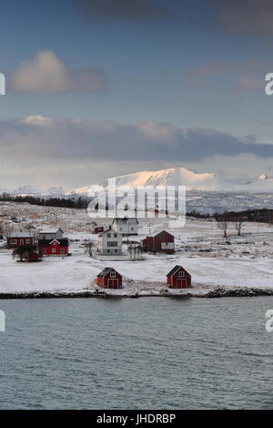 Case sul Holdoya-isola E.shore visto dalla frazione Ringen su Austvagoya-isola N.shore attraverso Hadselfjorden. Montagne di isola Hadseloya sfondo. Foto Stock