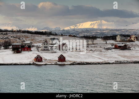 Case sul Holdoya-isola E.shore visto dalla frazione Ringen su Austvagoya-isola N.shore attraverso Hadselfjorden. Montagne di isola Hadseloya sfondo. Foto Stock