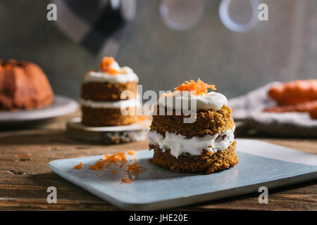 Mini torta di carote, farcito con crema di formaggio, sul blu piatto in calcestruzzo, su legno rustico Foto Stock