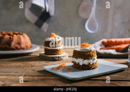 Mini torta di carote, farcito con crema di formaggio, sul blu piatto in calcestruzzo, su legno rustico Foto Stock