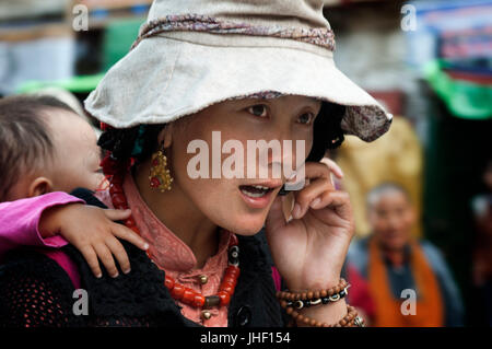 Una donna che porta il suo figlio per le strade di Lhasa. Bakhor square, Lhasa, in Tibet Foto Stock