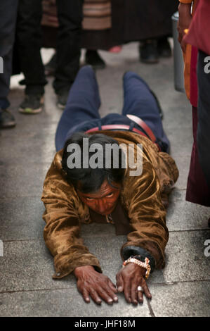 Il Tibetano dell uomo sta pregando sul terreno intorno al tempio di Jokhang, Lhasa il Tibet. Foto Stock