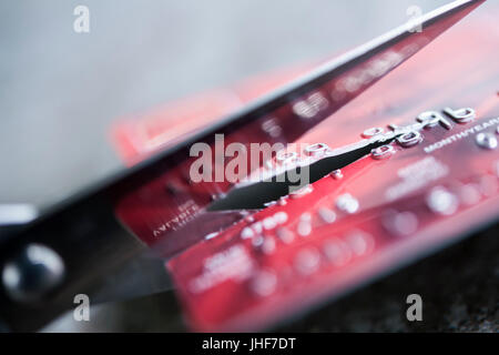 Carta di credito essendo tagliato con forbici, vicino. Foto Stock