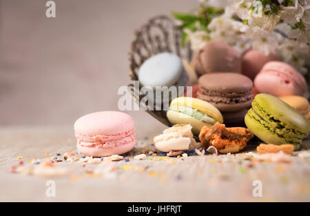 Amaretti multicolore su una tabella con vaso orientale e il ramo di ciliegio in fiore Foto Stock