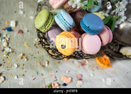 Amaretti multicolore su una tabella con vaso orientale e il ramo di ciliegio in fiore Foto Stock