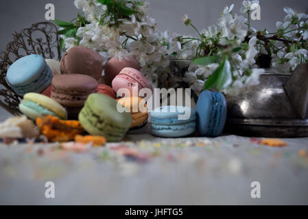 Amaretti multicolore su una tabella con vaso orientale e il ramo di ciliegio in fiore Foto Stock