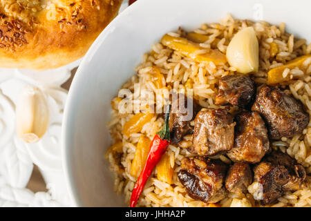 Uzbek Pilaf - riso con carne e verdure sul tavolo. Pilaf con carne di agnello e aglio zira. close up Foto Stock