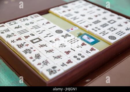 Set di piastrelle Mahjong '麻將' e scatola su sfondo di legno verde Foto Stock