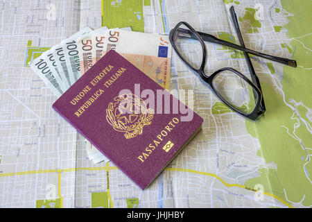 Pianificazione di un viaggio - passaporto italiano sulla mappa della città con le fatture in euro denaro e bicchieri Foto Stock