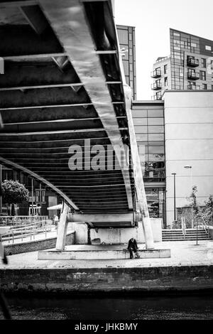 Senzatetto uomo sotto un ponte pedonale a Brewery Wharf, Leeds, West Yorkshire, Inghilterra. Foto Stock