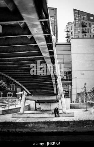 Senzatetto uomo sotto un ponte pedonale a Brewery Wharf, Leeds, West Yorkshire, Inghilterra. Foto Stock