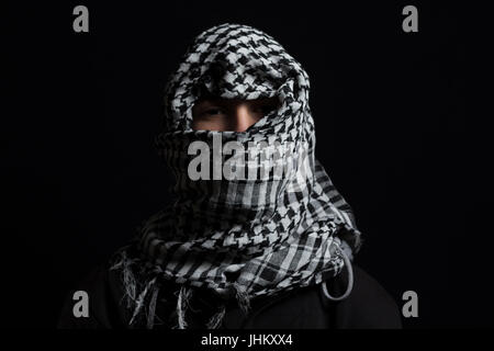 L'uomo nascosto con sciarpa palestinese sopra la testa di fronte isolato su sfondo nero Foto Stock