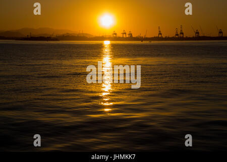 Rio de Janeiro, Brasile. 14 Luglio, 2017. Vista del tramonto nel pomeriggio invernale nella zona del porto di Rio de Janeiro. Carioca e turisti guardare il tramonto sulle rive della Baia di Guanabara, nel centro di Rio. Nonostante l'inverno temperature in città sono i 28 gradi Celsius gamma. In questa immagine: set di sole e foglie intensa riflessione in acque inquinate della baia di Guanabara. Credito: Luiz Souza/Alamy Live News Foto Stock