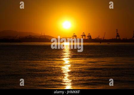 Rio de Janeiro, Brasile. 14 Luglio, 2017. Vista del tramonto nel pomeriggio invernale nella zona del porto di Rio de Janeiro. Carioca e turisti guardare il tramonto sulle rive della Baia di Guanabara, nel centro di Rio. Nonostante l'inverno temperature in città sono i 28 gradi Celsius gamma. In questa immagine: set di sole e foglie intensa riflessione in acque inquinate della baia di Guanabara. Credito: Luiz Souza/Alamy Live News Foto Stock