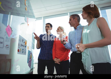 Basso angolo di visione degli imprenditori a discutere sulla lavagna in ufficio durante la giornata di sole Foto Stock