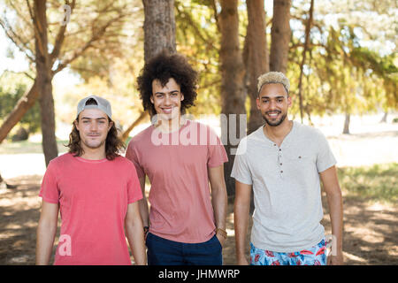 Ritratto di sorridente amici maschi in piedi a fianco a fianco in foresta Foto Stock