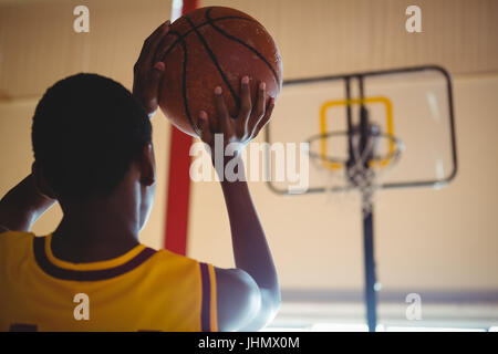 Vista posteriore del ragazzo adolescente giocando a basket in tribunale Foto Stock