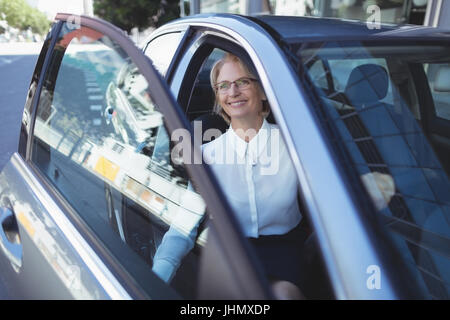 Imprenditrice sorridente che guarda lontano mentre esce dalla macchina Foto Stock
