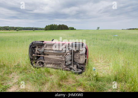 Auto rottamata giacente sul lato in un campo di grano Foto Stock