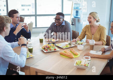 Happy business colleghi avente il pranzo sul tavolo in ufficio caff Foto Stock