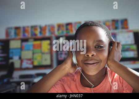 Close up ritratto di ragazzo ascoltare musica con le cuffie in aula Foto Stock