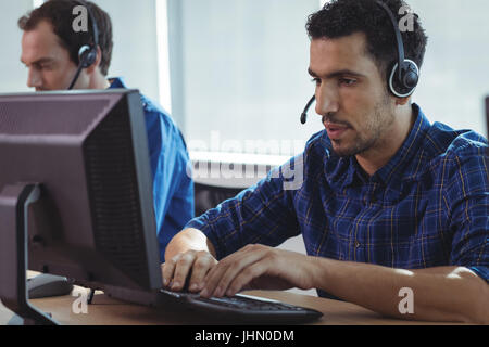 Imprenditore focalizzato lavorando sul computer alla reception in call center Foto Stock