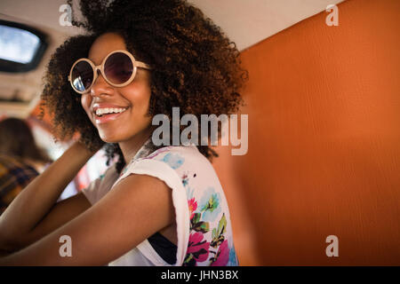 Giovane donna sorridente indossando occhiali da sole seduti in camper Foto Stock