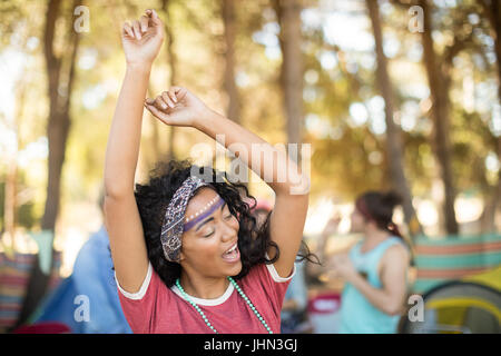 Donna felice ballando con le braccia sollevate al campeggio Foto Stock