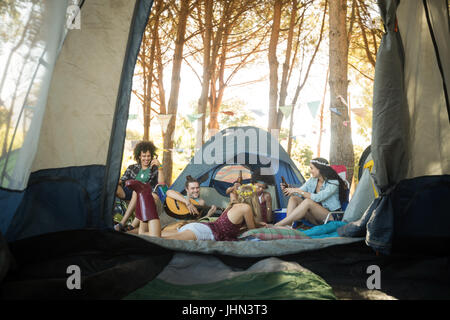 Felice giovani amici godendo insieme al campeggio visto attraverso la tenda Foto Stock