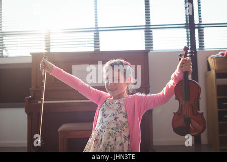 Ritratto sorridente ragazza con il violino con le braccia aperte in aula di musica Foto Stock