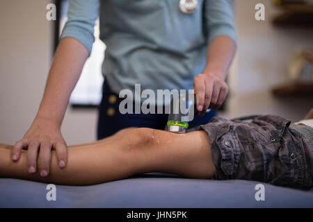 Sezione mediana del ragazzo ricevendo ultrasuoni scansione dal terapista del sesso femminile in ospedale Foto Stock