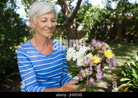 Sorridente donna senior azienda fresco bouquet di fiori in cortile Foto Stock