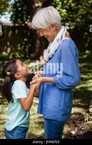 Vista laterale della nonna e la figlia in piedi tenendo le mani sul cortile Foto Stock