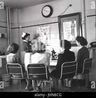 Degli anni Cinquanta, Inghilterra, storico, quattro femmine gli studenti che frequentano una scuola di formazione per insegnanti di ascoltare un infermiere spiegare circa gli alunni delle scuole di denti e come identificare i potenziali problemi. Foto Stock