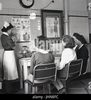 Degli anni Cinquanta, Inghilterra, storico, quattro femmine gli studenti che frequentano una scuola di formazione per insegnanti di ascoltare un infermiere spiegare circa gli alunni delle scuole di denti e come identificare i potenziali problemi. Foto Stock