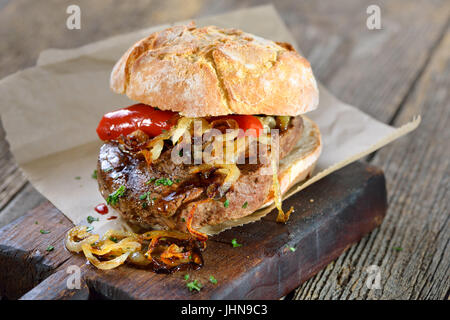 Grandi sandwich a base di carne: manzo alla griglia filetto di manzo con anelli di cipolla fritti su un nuovo rotolo Foto Stock