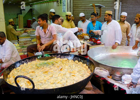 Uomo kachori frittura in tondo grande padella ovvero Karahi, per la festa musulmana di Eid al-fitr, gli acquirenti in attesa di essere preparato Foto Stock