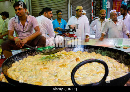 Uomo kachori frittura in tondo grande padella ovvero Karahi, per la festa musulmana di Eid al-fitr, gli acquirenti in attesa di essere preparato Foto Stock