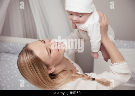 Ritratto di un simpatico bionda madre a giocare con i suoi adorabili baby a casa felice mom sollevando il suo piccolo figlio, godendo della genitorialità Foto Stock