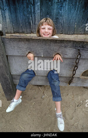 Una giovane ragazza bloccato in una gogna o insieme di titoli, alla Piantagione Plimoth, Massachusetts, Foto Stock