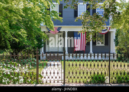 Vecchio sag harbor home sulla strada principale con bandiere patriottico e una bandiera americana visualizzati sul portico anteriore Foto Stock