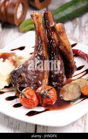 Arrosto di agnello gambo con patate arrosto e carote di stile e in un ambiente rustico Foto Stock