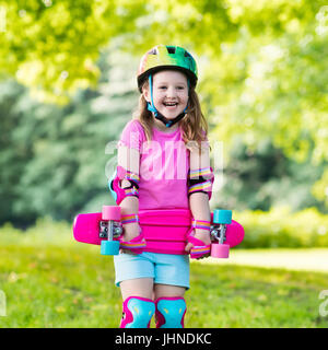 Equitazione per bambini skateboard in estate park. Bambina di imparare a cavalcare skateboard. Active outdoor sport per la scuola e per la scuola materna i bambini. Bambini skat Foto Stock