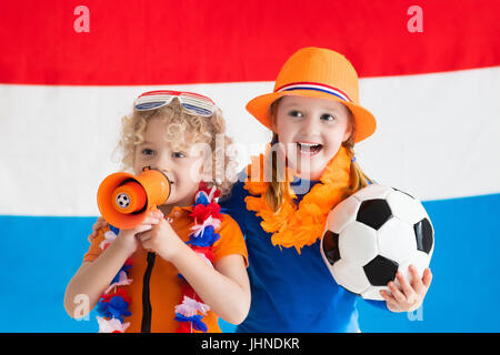 Bambini il tifo e il supporto di calcio olandese team. I ragazzi appassionati e sostenitori del Paesi Bassi durante il campionato di calcio. Un ragazzo e una ragazza da Hollan Foto Stock